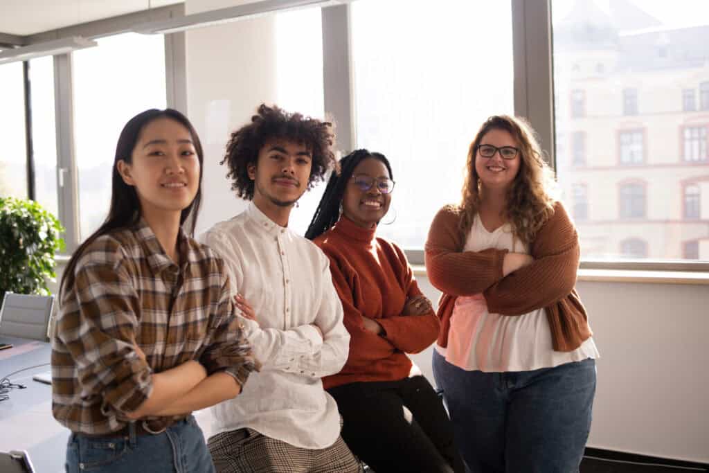 A group of young colleagues in the office are looking at the camera