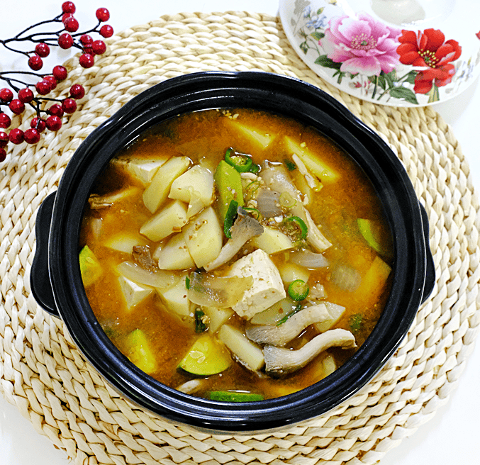 A steaming hot Korean soybean paste stew in a stone pot.