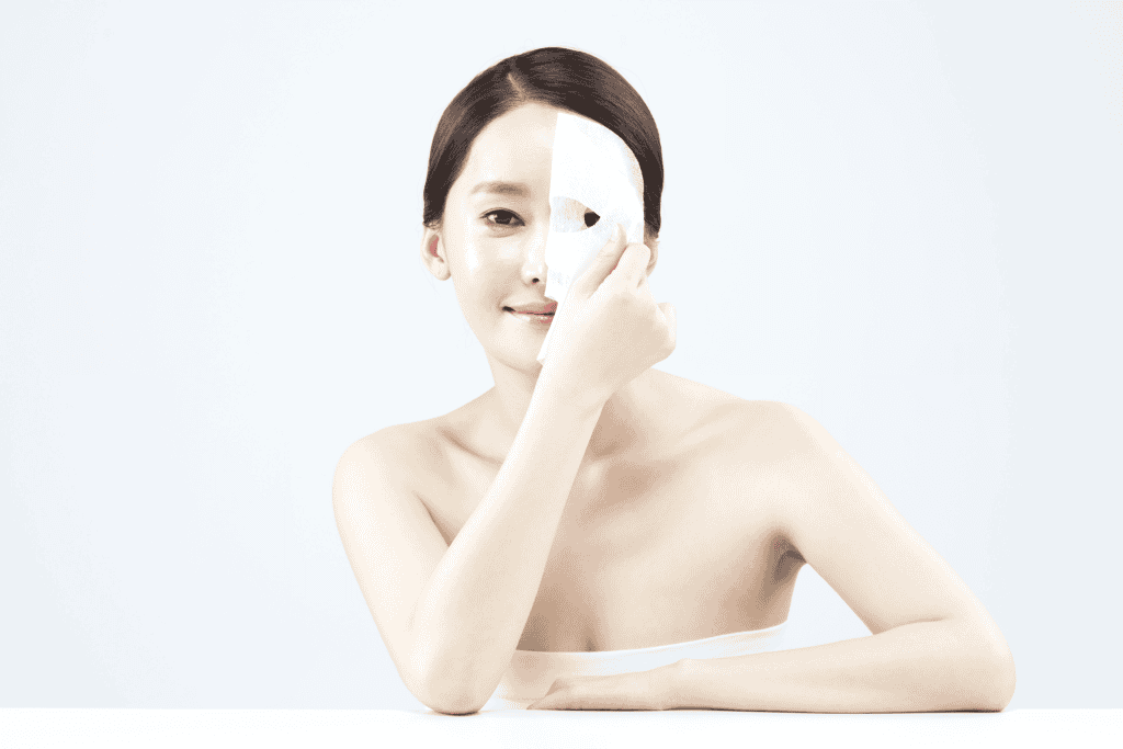 Woman applying a Korean sheet mask for skincare.