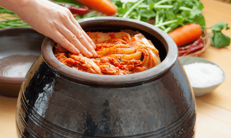 Kimchi being packed into a jar for fermentation.