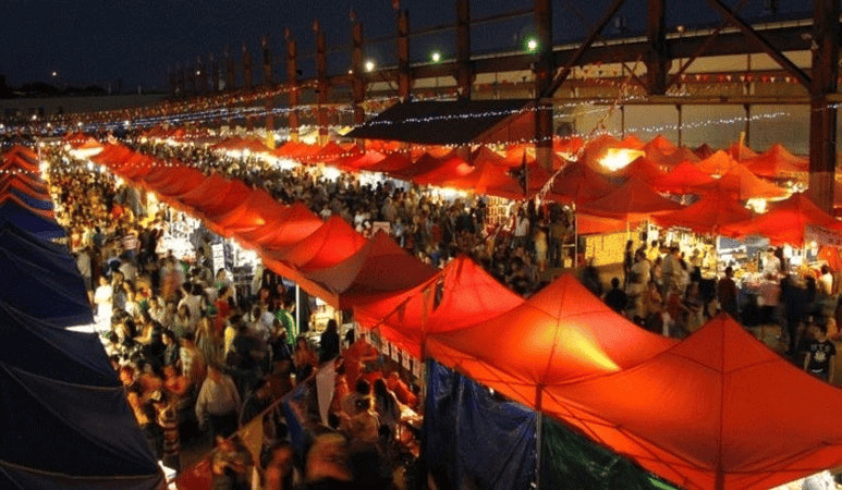 Korean street food stalls with steaming dishes and people gathered.