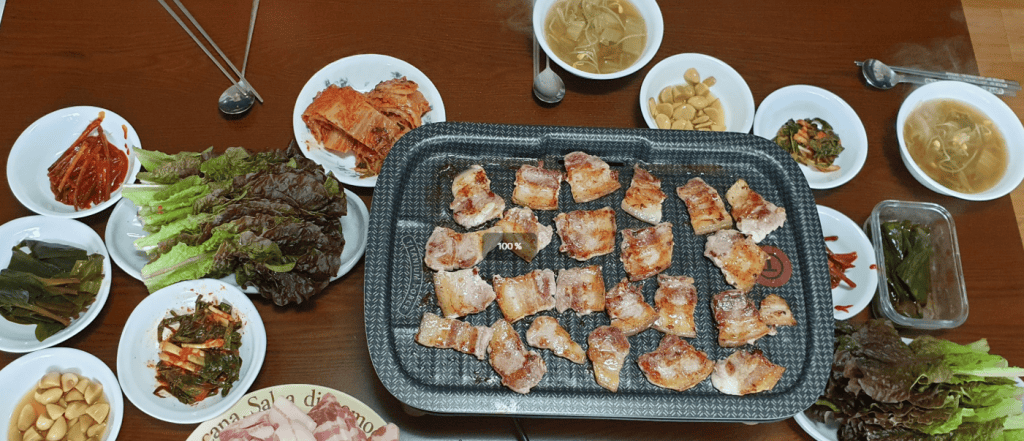 Pork belly slices grilling on a Korean BBQ pan.