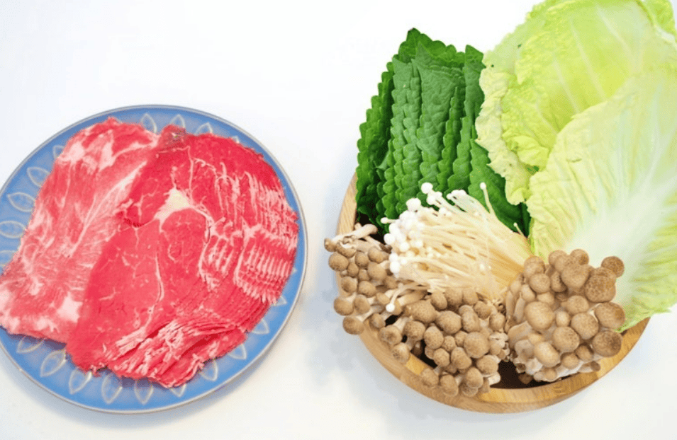 Fresh vegetables like napa cabbage and zucchini alongside sliced beef.