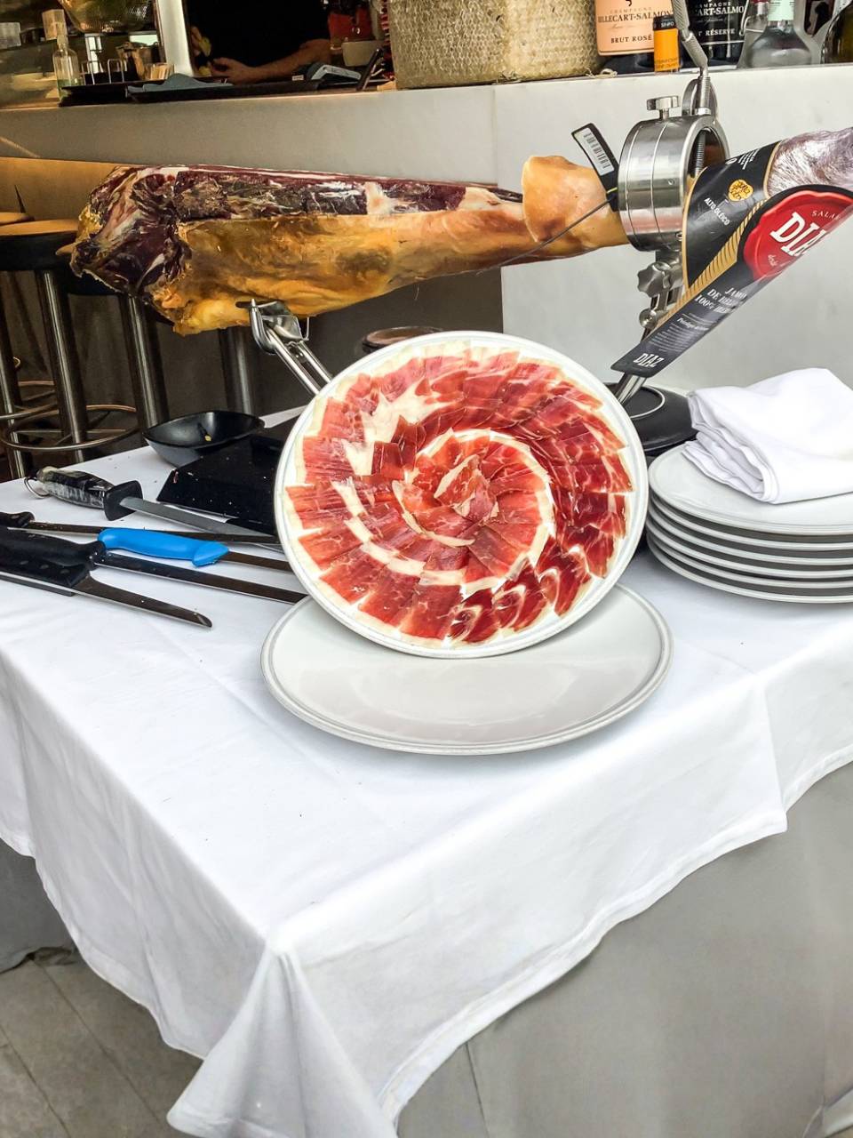 Plato de Jamón Ibérico de Bellota cortado a cuchillo y presentado artísticamente en espiral junto a la pieza entera en la barra de KRAM Andorra.