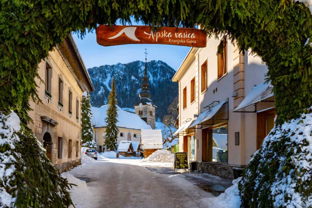 a snowy street with buildings and a sign