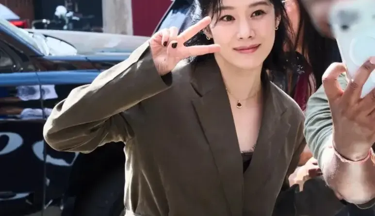 Kim Hyun-joo smiling and making a V sign outdoors