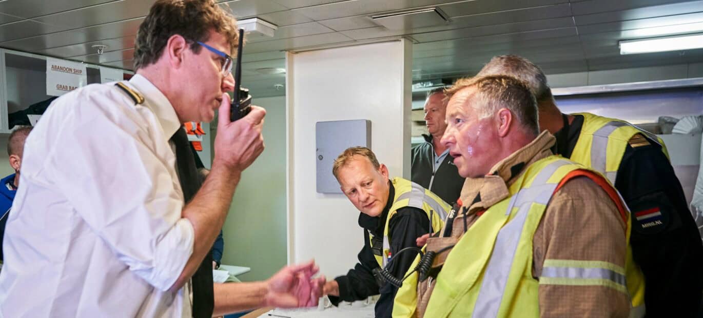 Brandweermensen praten op de brug met de kapitein