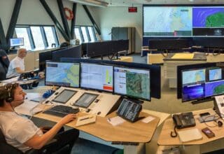 Op het Kustwachtcentrum staan meerdere tafels met schermen, informatie- en communicatiesystemen.