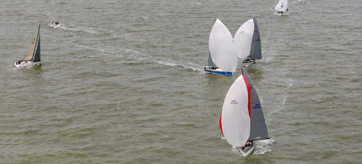 Meerdere zeilschepen doen mee aan een evenement op zee.