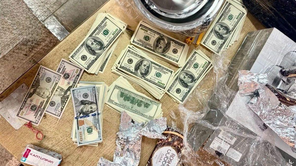 Стіл із розкладеними пачками доларів США, вилучених під час обшуку
