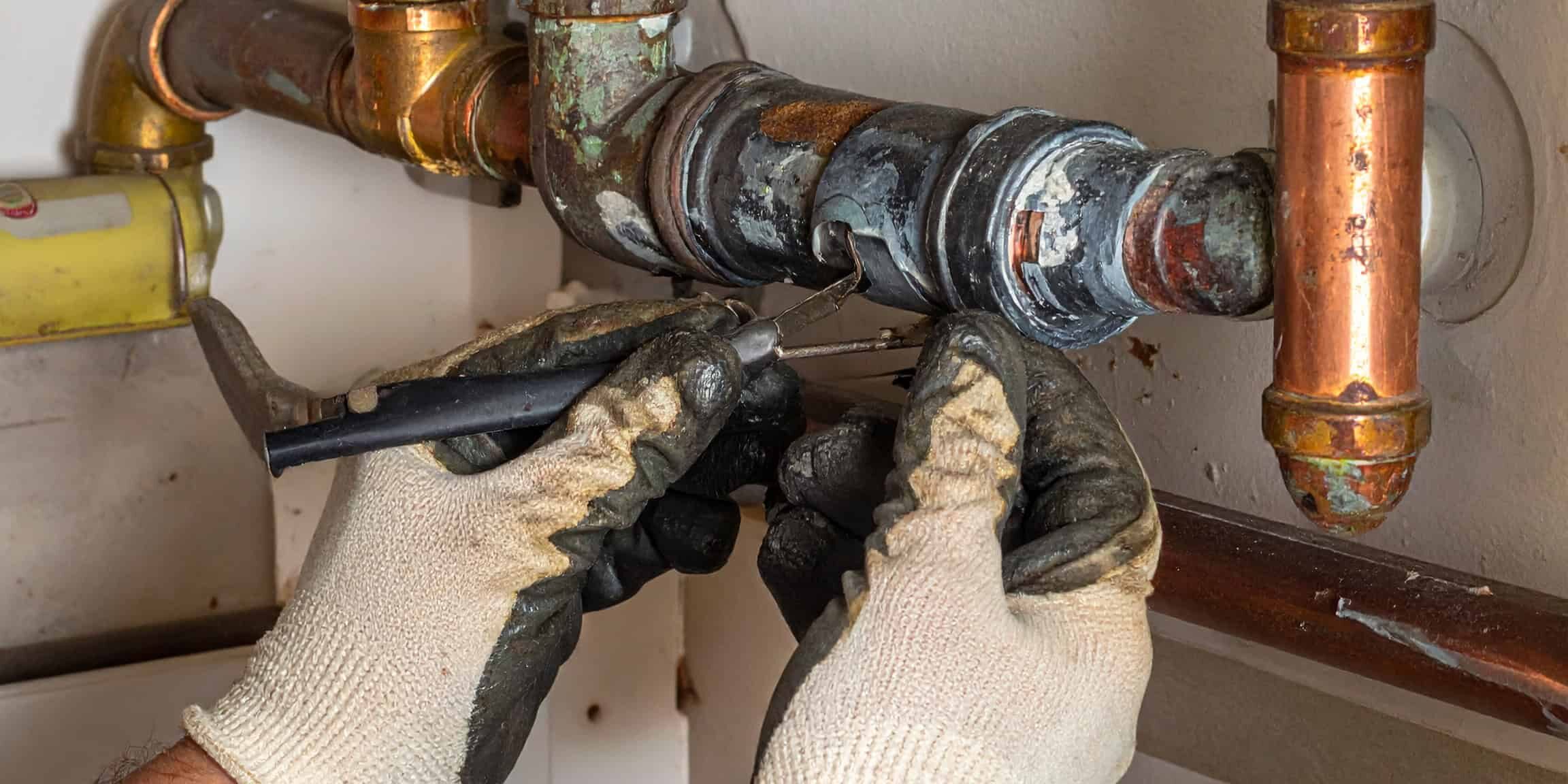 Firefly_Close-up of gloved hands inspecting corroded copper pipes inside a residential wall, 213812