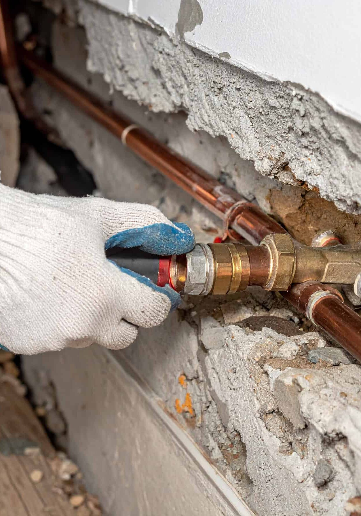 Firefly_Close-up of gloved hands repairing a leaking copper water pipe beneath a concrete sla 623784