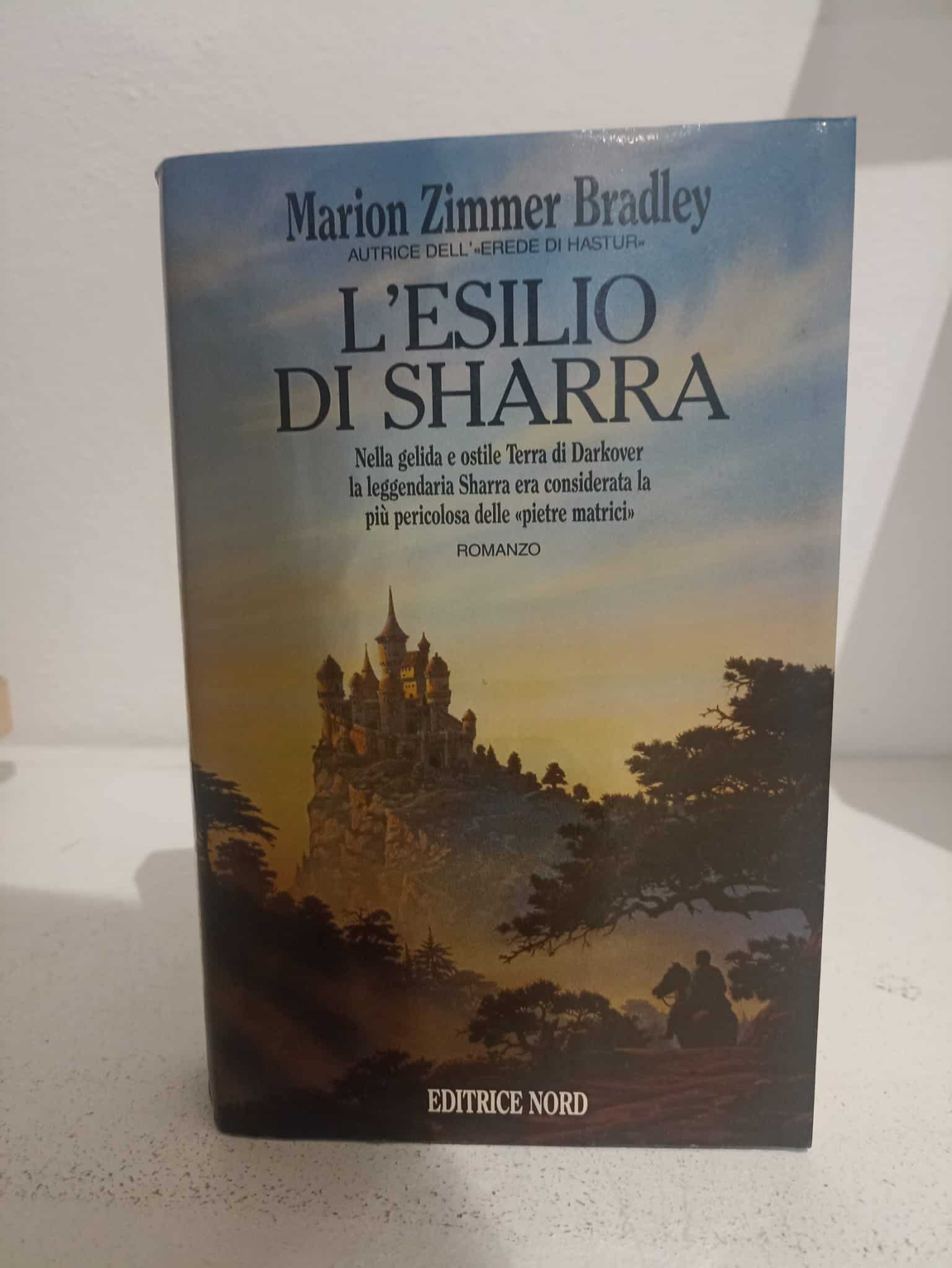 Alt: Copertina romanzo "L'esilio di Sharra" di Marion Zimmer Bradley, castello e paesaggio fantasy.