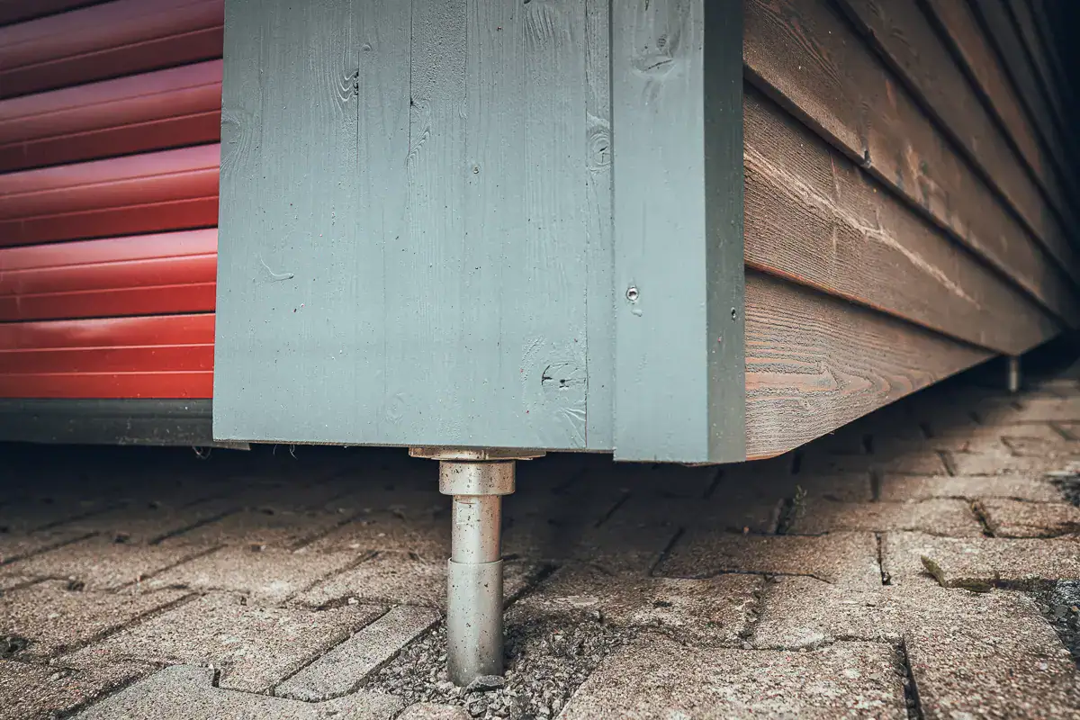 Detailansicht: Lauffers klassisches Bauprojekt: moderner Carport in Holzverschalung mit Stützfüßen für den konstruktiven Holzschutz.