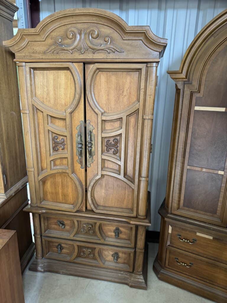 Vintage wooden wardrobe with ornate carvings and brass handles. Perfect for antique furniture collec.