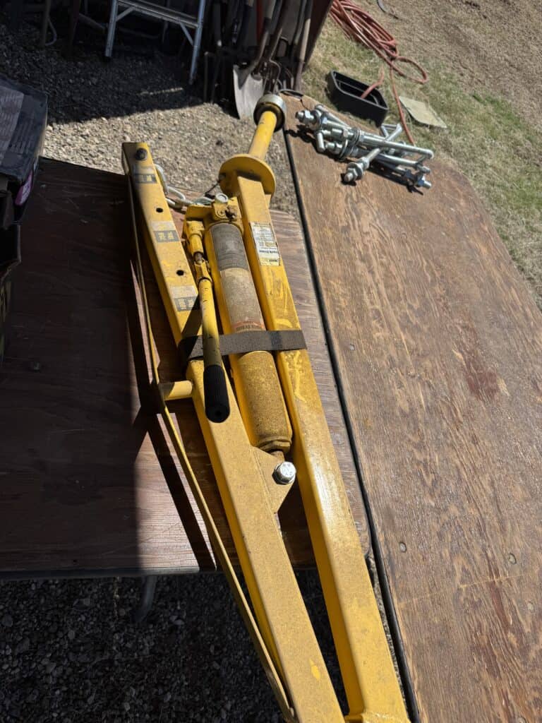 Hydraulic jack with yellow frame and control handle.