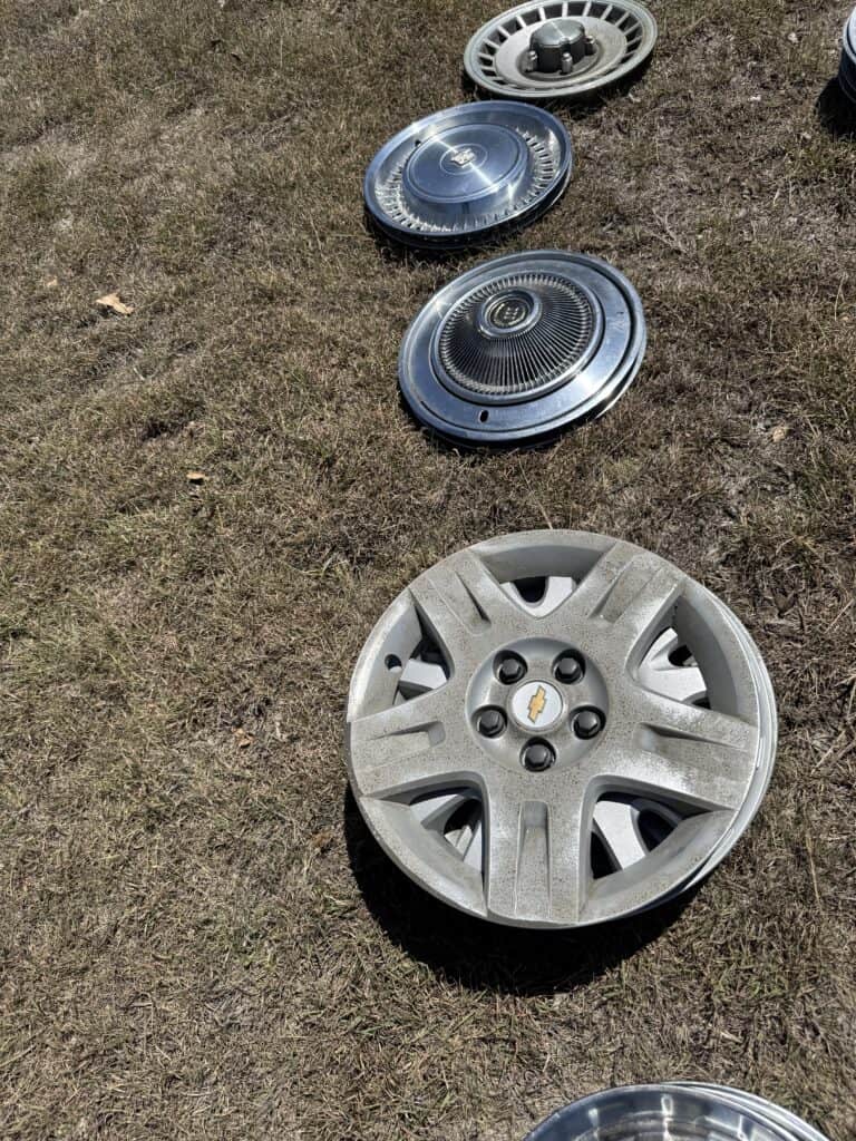 Wheel covers and hubcaps for vehicles, laid out outdoors.