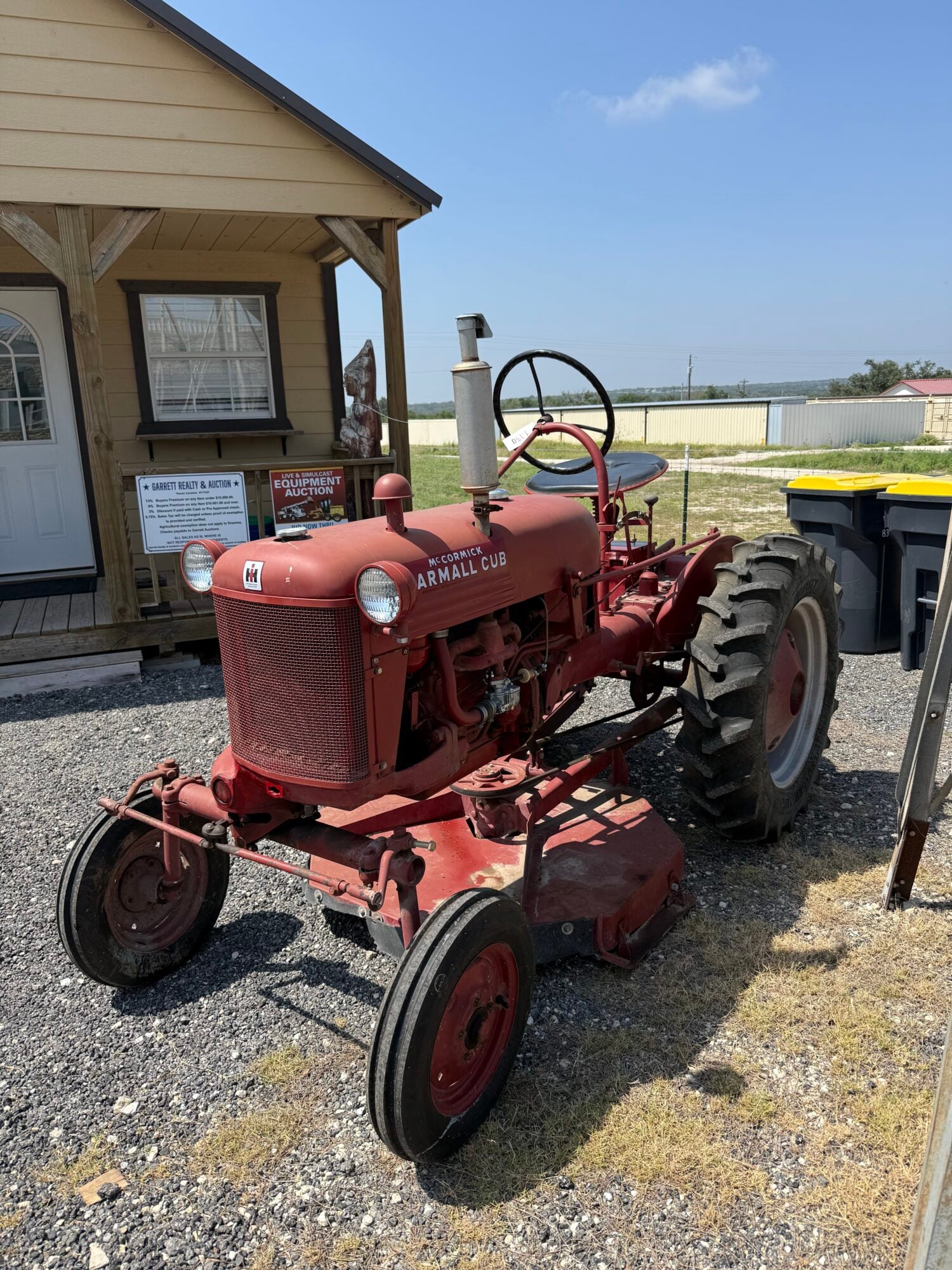 Red vintage farm tractor with large rear tires and steering wheel.