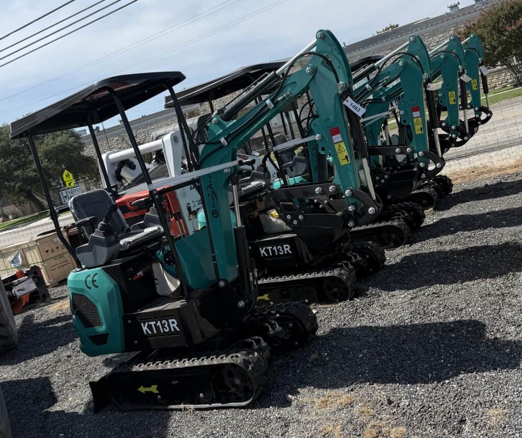 Row of teal mini excavators with black tracks at equipment auction.