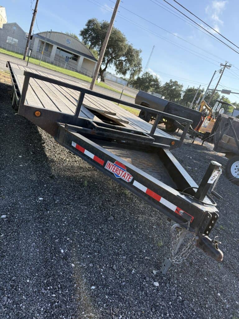 Black utility equipment trailer with wooden deck and safety rails.
