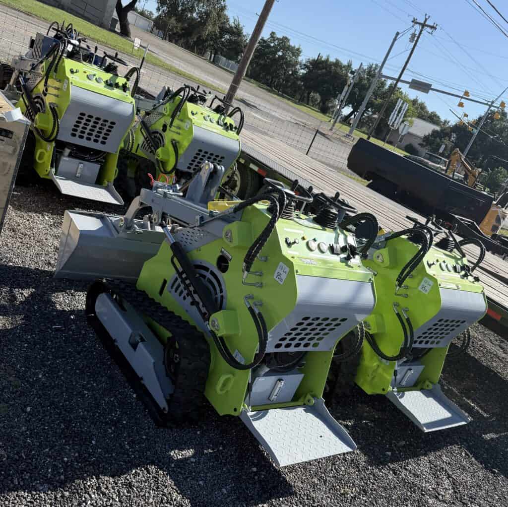 Bright green compact track loaders displayed outdoors for auction.