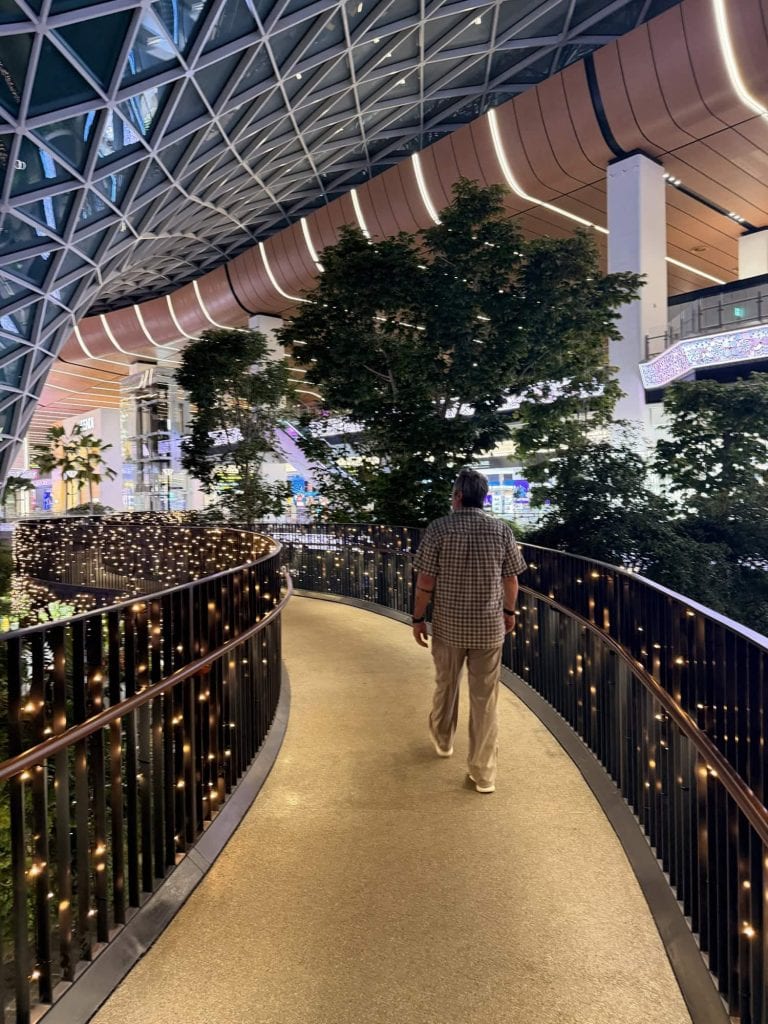 Indoor shopping mall with lush trees and innovative architecture.