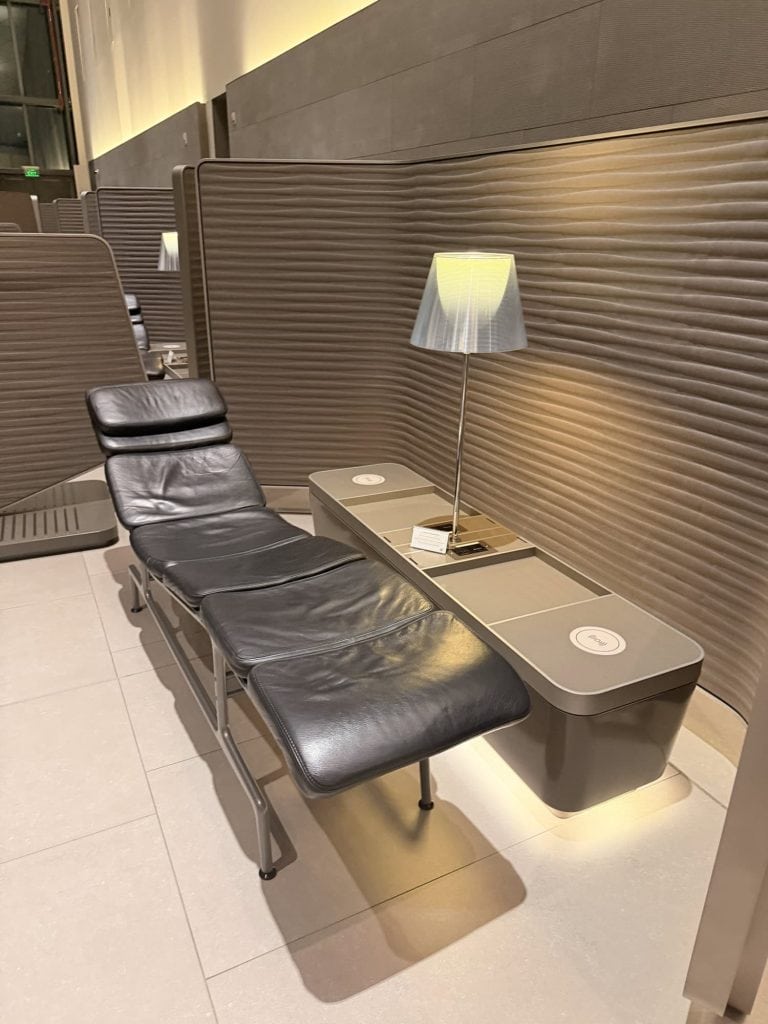 Comfortable black lounge chair with side table and lamp in modern airport lounge.