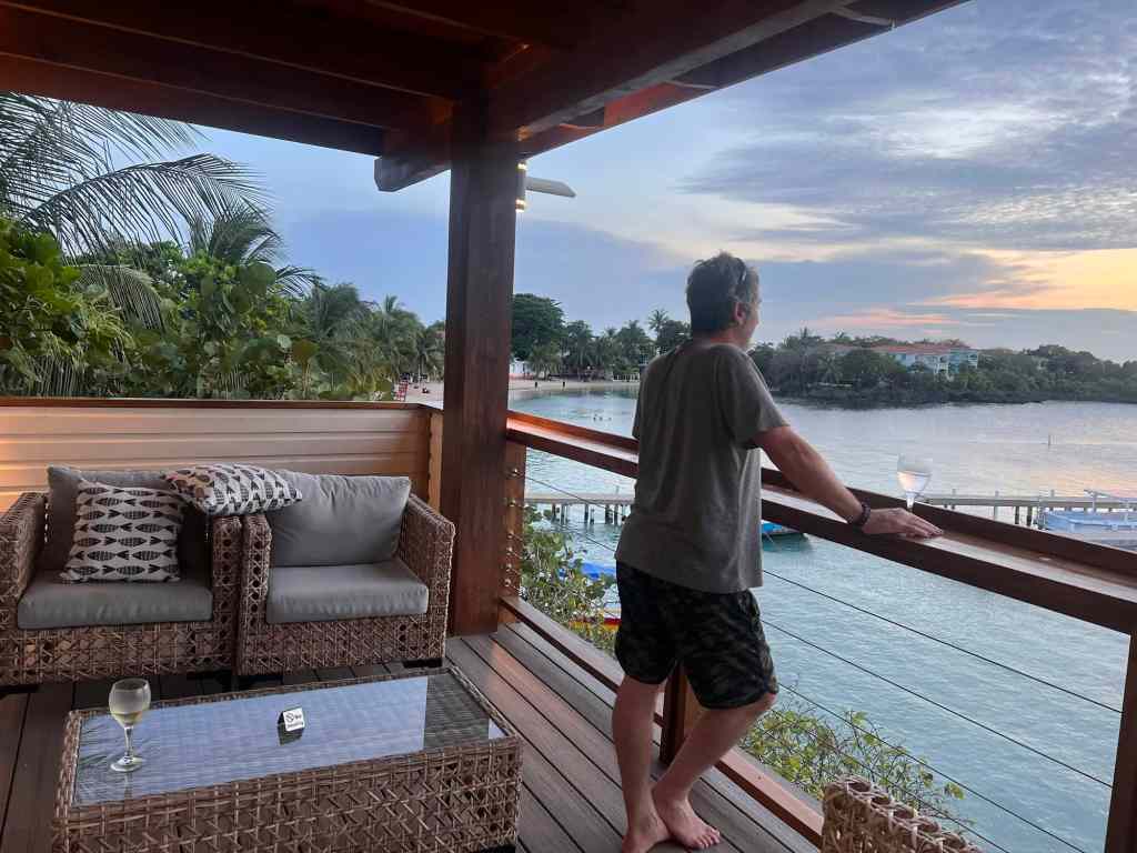 Relaxing river view with man enjoying sunset on balcony.