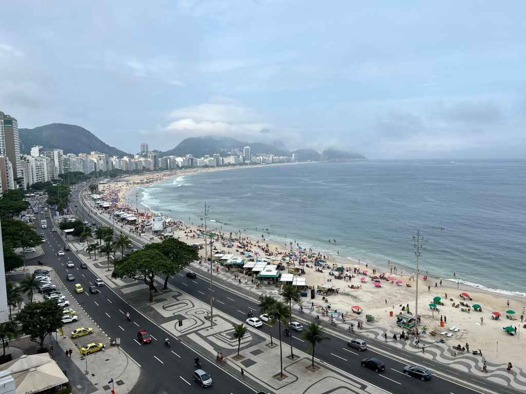 Beach and city skyline with mountains, busy shoreline, and coastal road in a vibrant seaside setting.