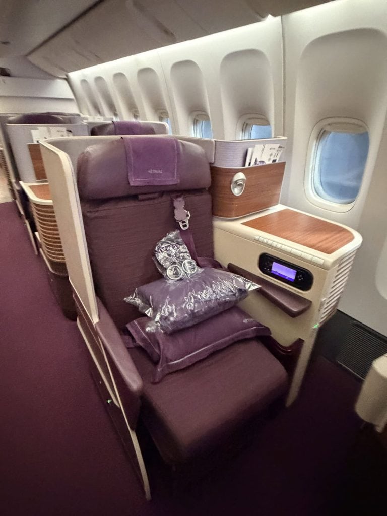 Premium airplane seat with plush cushions, pillows, and in-flight entertainment.