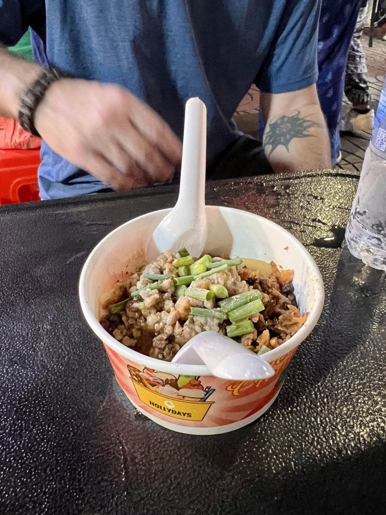 Asian noodle bowl with vegetables and meat in a takeout container.