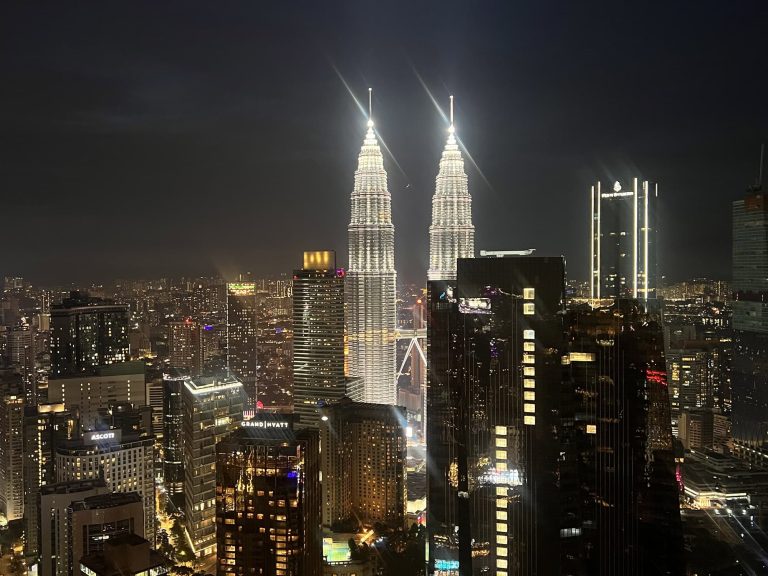 Petronas Towers Kuala Lumpur night skyline with illuminated skyscrapers.