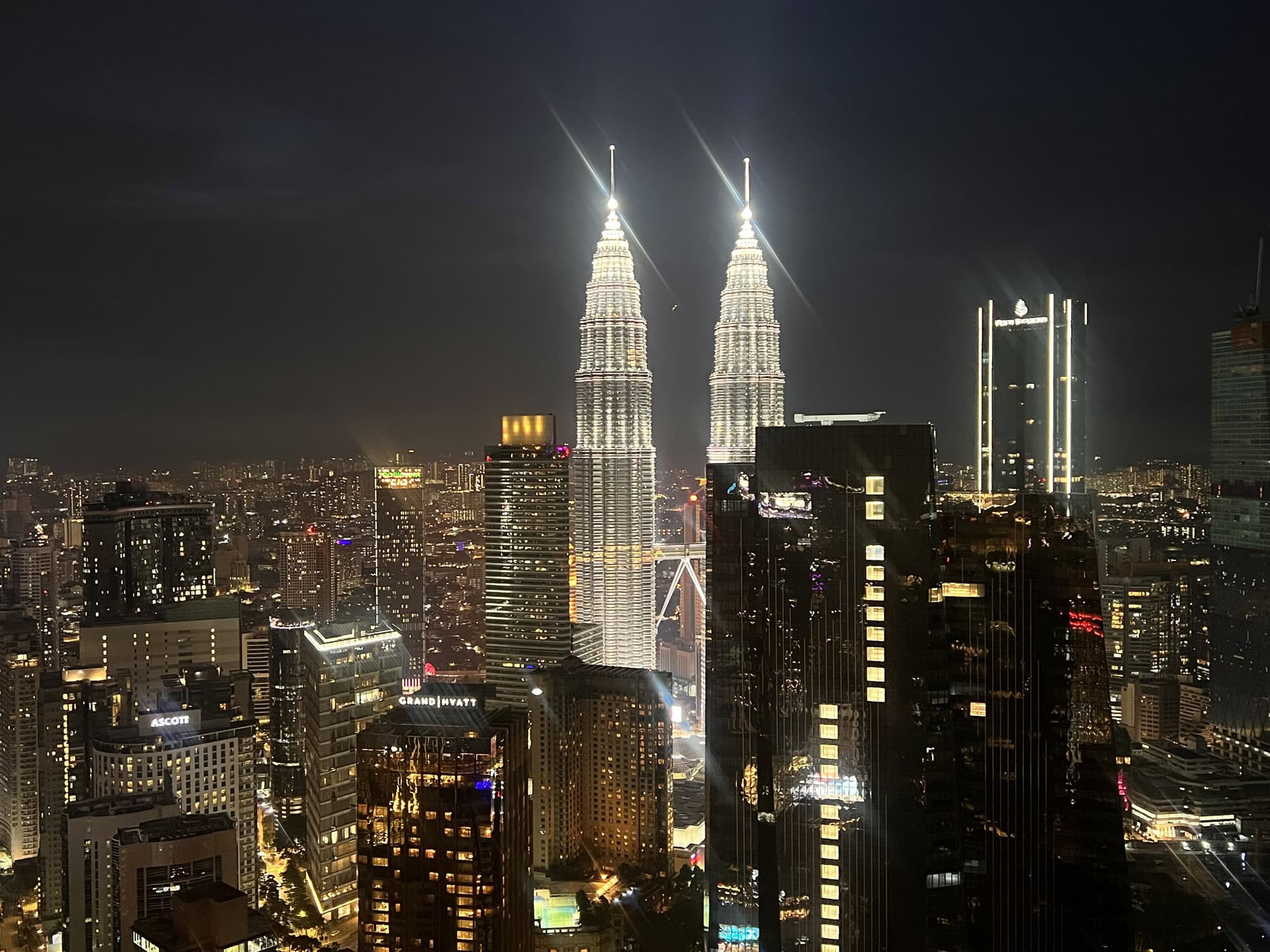 Petronas Towers Kuala Lumpur night skyline with illuminated skyscrapers.