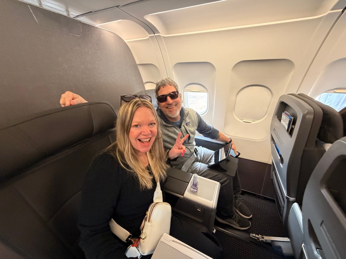 Airplane interior with two smiling passengers seated comfortably.