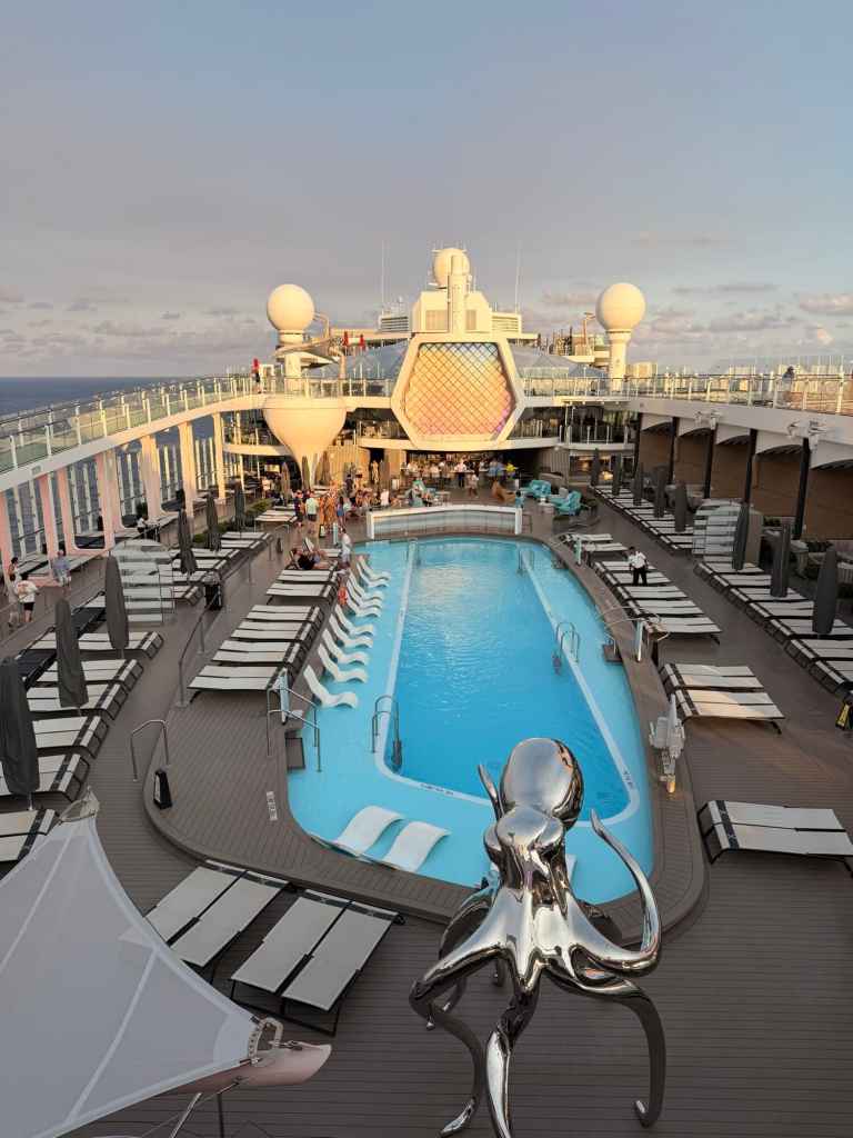 Elegant cruise ship deck featuring a large swimming pool, sun loungers, and stylish decor for a rela.