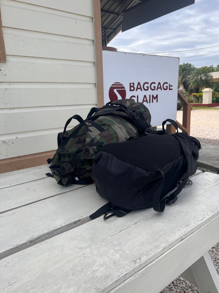 Baggage claim area with two travel backpacks on a white wooden table, ready for pickup.