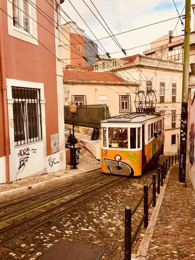 Vintage tram in a historic city street with colorful buildings and cobblestone pavement.
