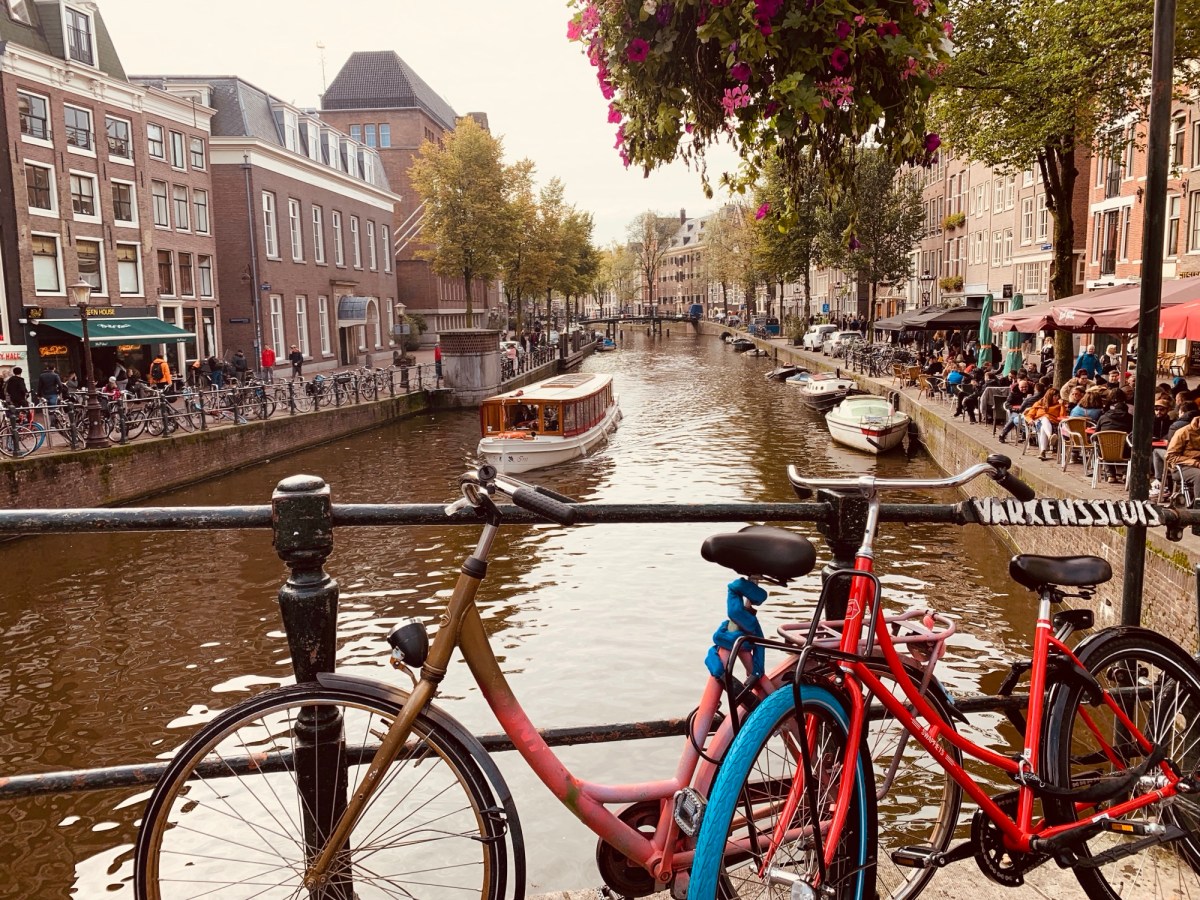 Bicycles parked along a canal in Amsterdam during sunset.