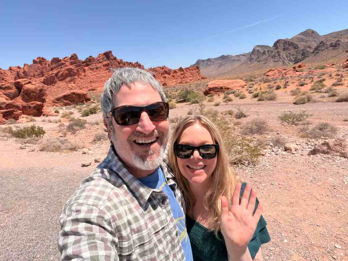 Happy couple exploring the red rock desert landscape during their travel adventure.