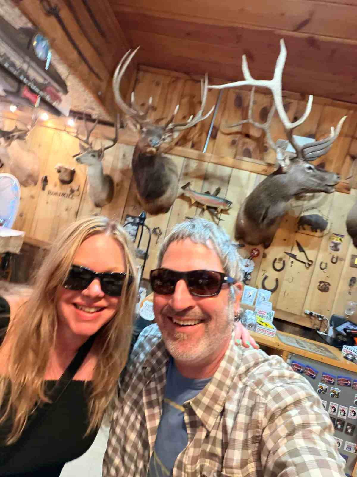 Deer heads mounted on the wooden wall with antlers in a rustic setting.