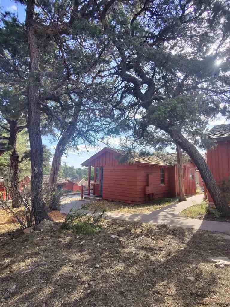 Charming red cabin surrounded by trees in a peaceful outdoor setting.