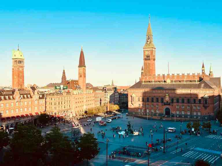 Panoramic view of Munich's historic city square with towers and busy streets.