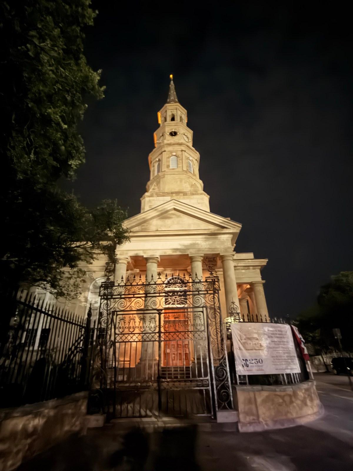 Night view of historic church with illuminated tower and classical architecture.