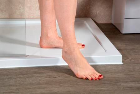 Image showing the feet of a person stepping out of a low level shower tray. Life Quality Bathing.