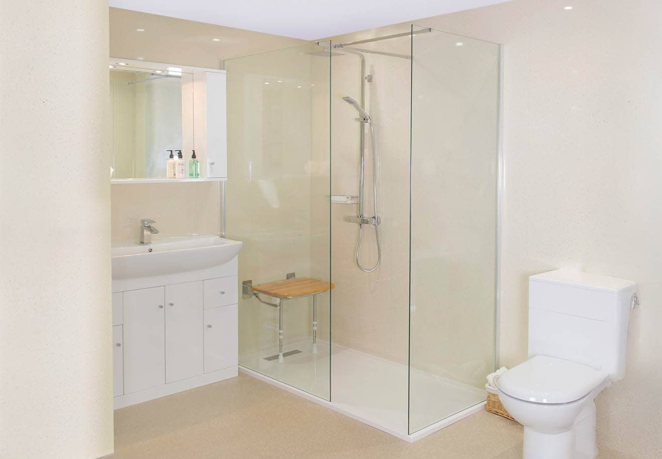 Accessible bathroom with glass-enclosed shower, wooden fold down bench, wall-mounted shower head, and white vanity with mirror.
