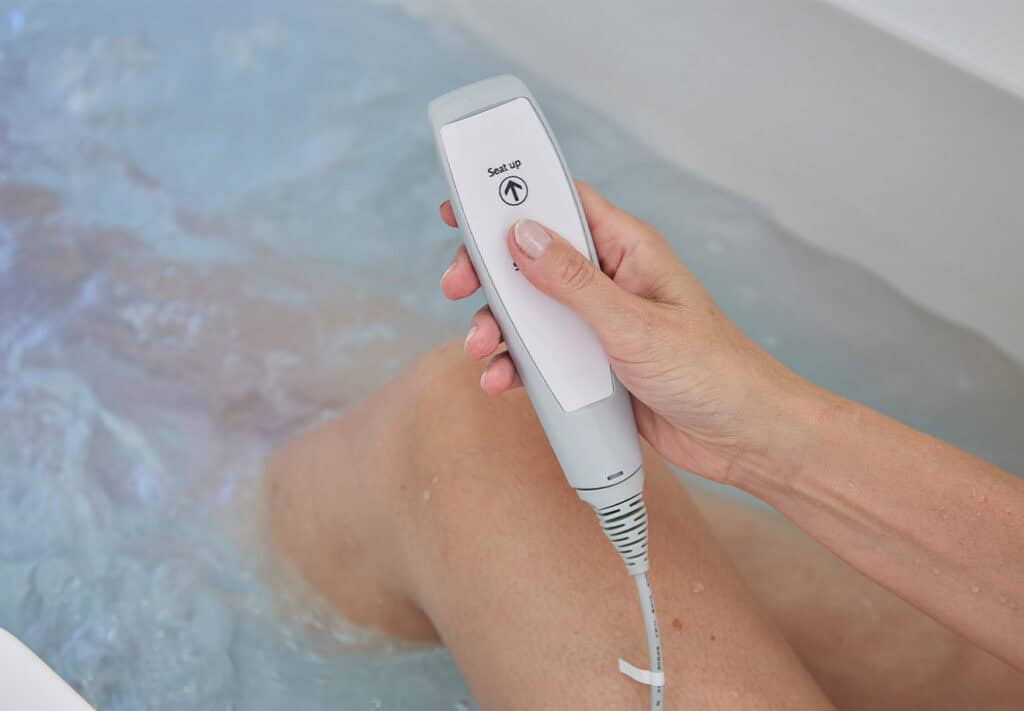 Hand held remote for raising seat up and down being held by person bathing.
