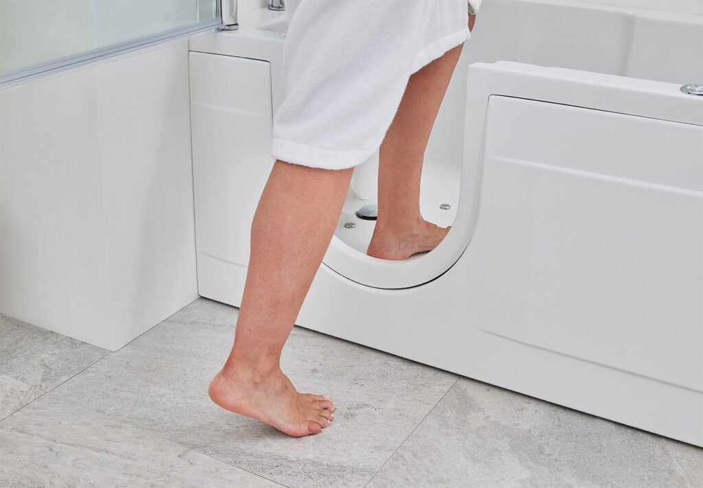 Pair of legs in robe walking into bath through low level open door.
