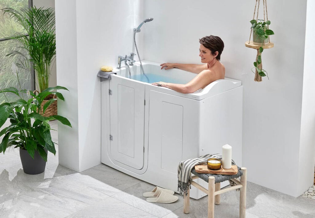 Elderly person bathing in a compact bath. Arms relaxed and laid back around sides of bath