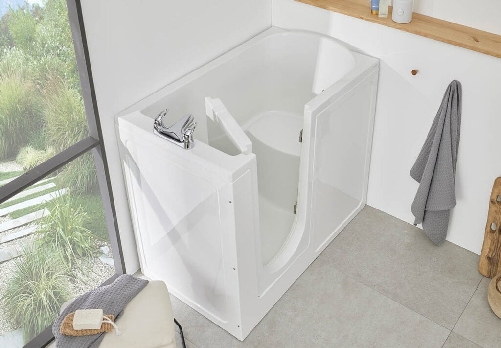 Milano Ampio (Oregon) product image aerial view. Compact walk in bathvwith door open in modern bathroom, large wall sized window, grey bowl hanging from wall with plant and other decorative pieces on long shelf indented into wall.