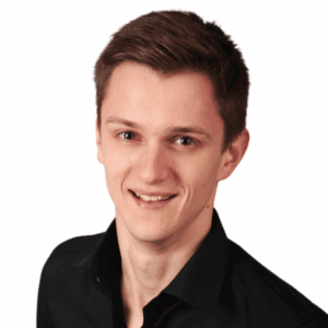 Patrick Sosath Co-Founder - Young man smiling, dressed in black shirt, professional headshot for real estate investment firm.